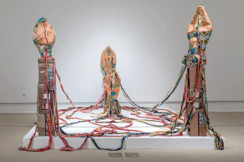 A sculptural installation on a gallery platform. Media: earthenware ceramics and fabrics.