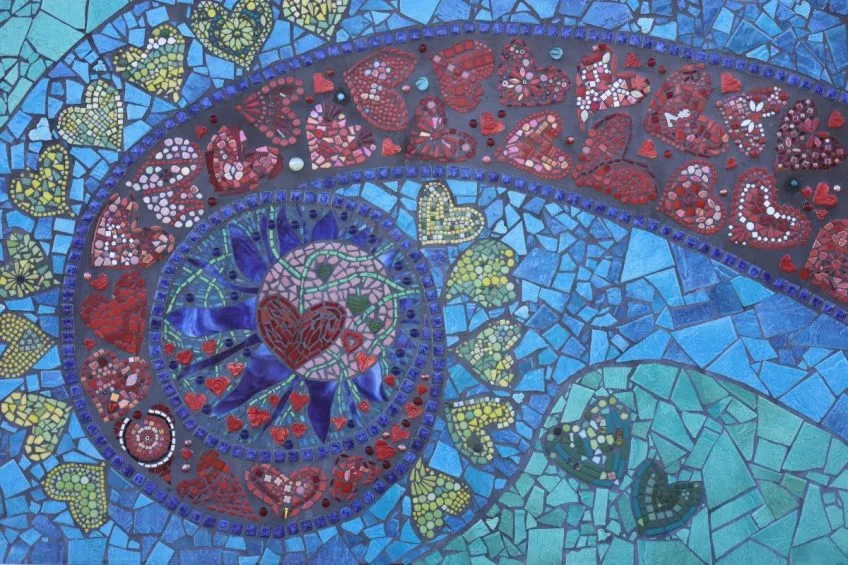 Detail of a mosaic with red and yellow hearts on a blue background.