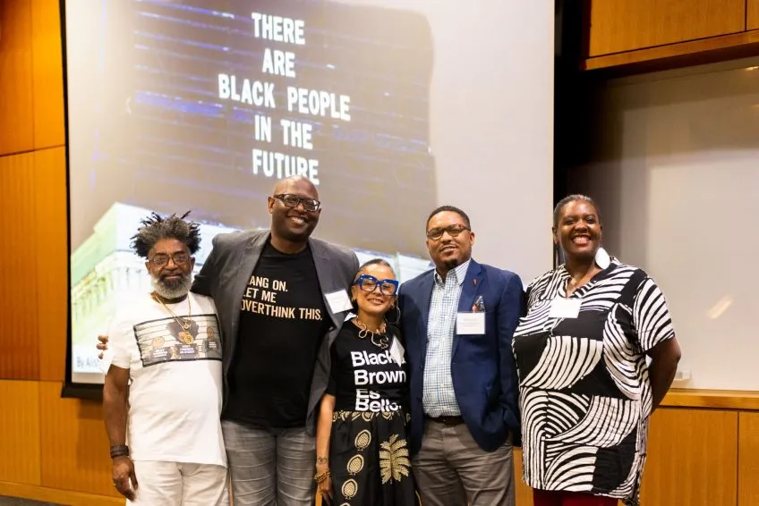Five people standing in front of projector text that reads 