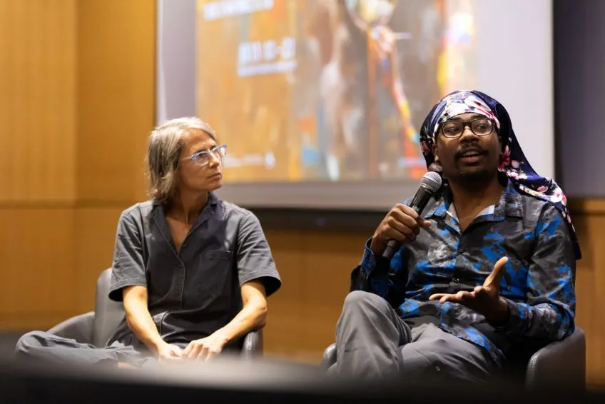 Two people in seated conversation on a conference stage.