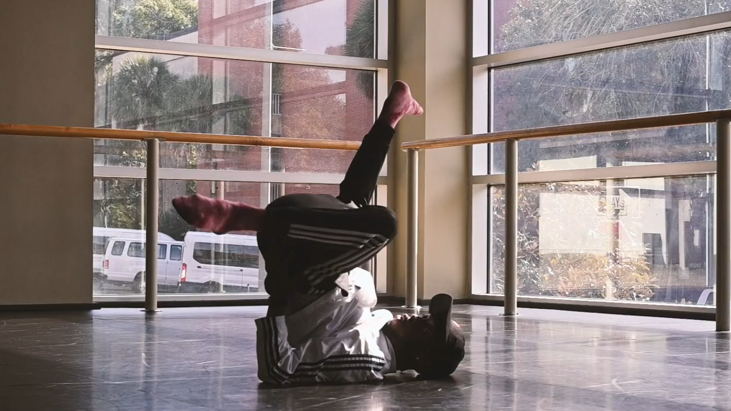Video still of a person breakdancing with their head and shoulders on the ground and legs raised