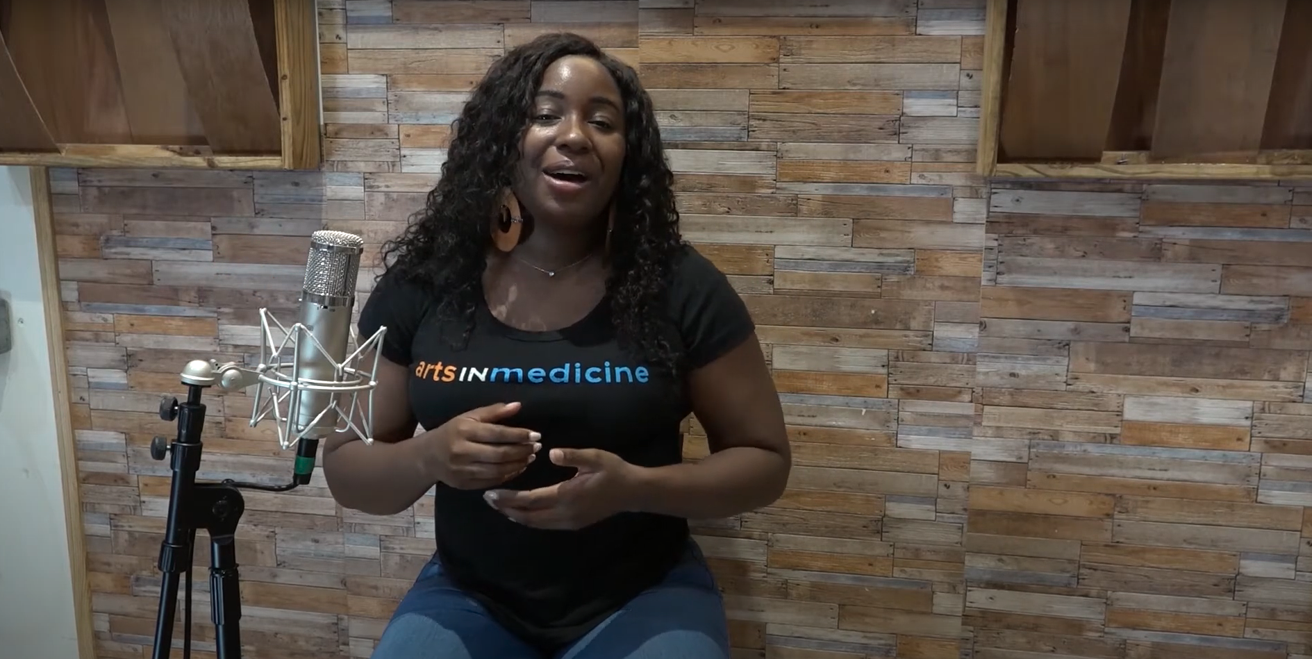 A woman wearing an Arts in Medicine T-shirt sings into a microphone