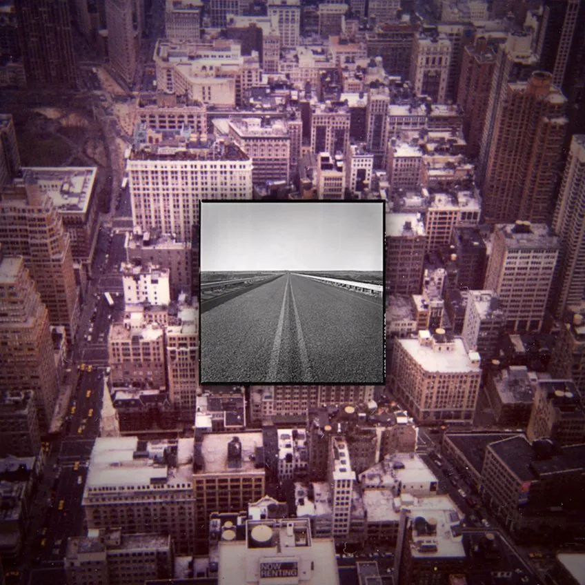 A small black and white photo of an empty desert road positioned on top of a desaturated photo of a busy city from a bird's eye view