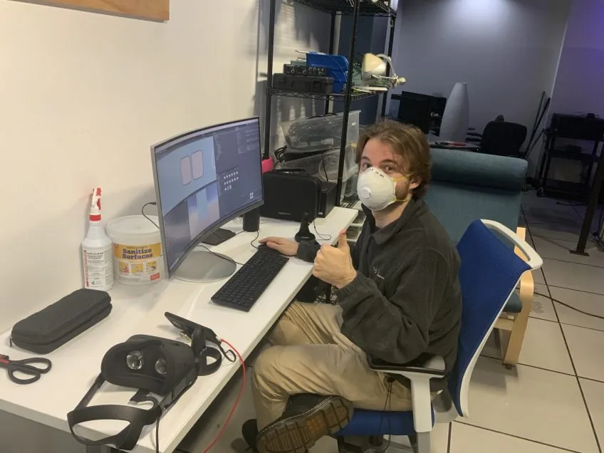 A person working at a computer giving a thumbs up sign