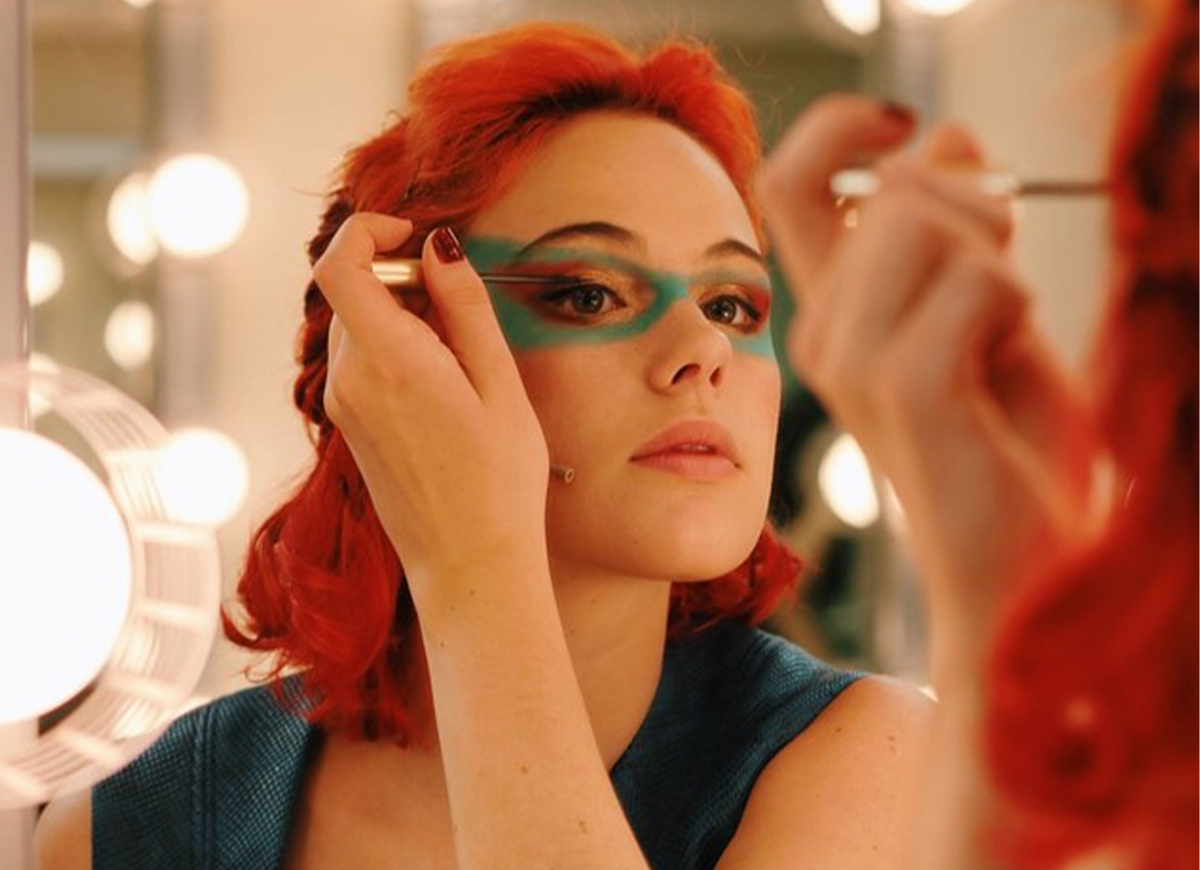 An actor applies stage makeup around her eyes