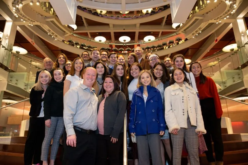 A group of approximately 25 people on theatre steps