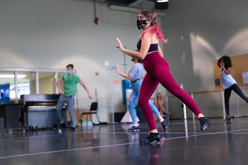 Tap dancers wearing face masks practice in a studio