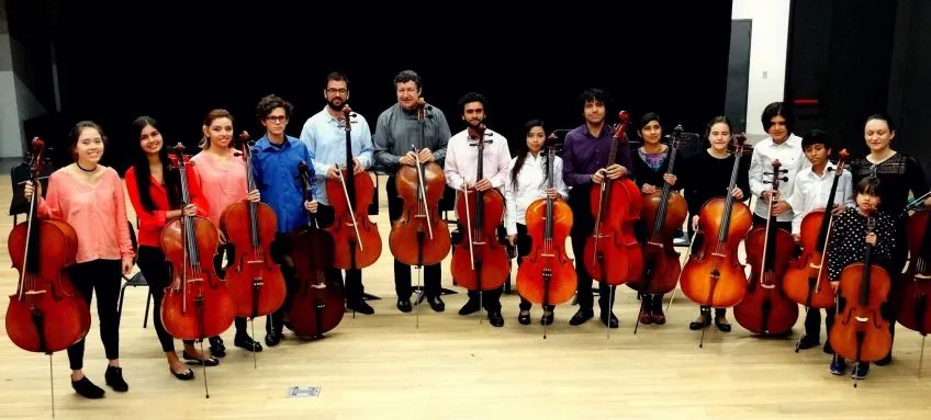 All-ages group of 15 people holding cellos