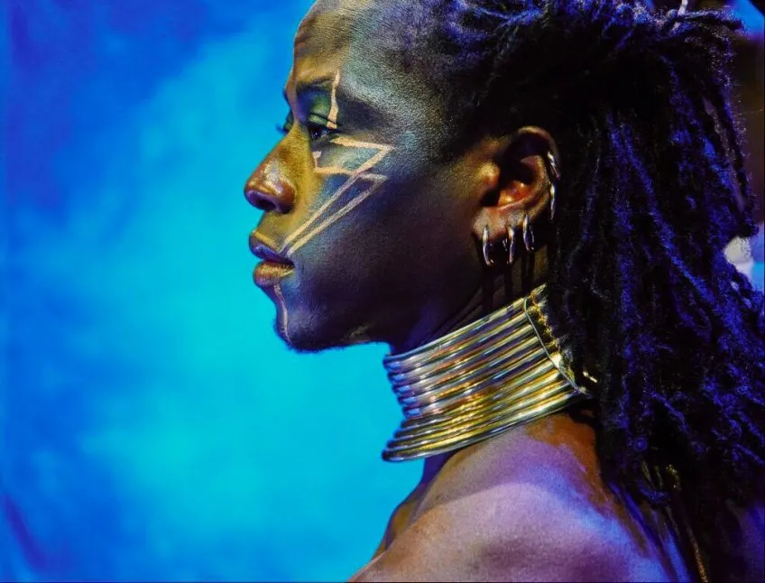 A person wearing West African accessories and makeup shown in profile from shoulders up