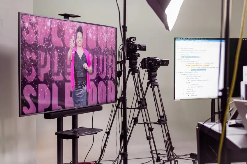 A large monitor displays College dean Onye Ozuzu raising a champagne toast in the Splendor livestream.