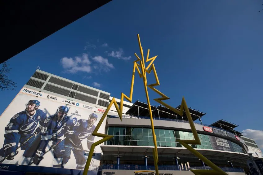 A large metal lightning sculpture in front of a building with photos of hockey players from floor to ceiling
