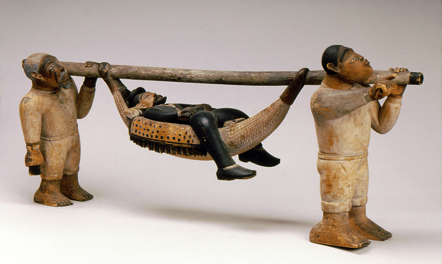 Sculpture of a man in suit, laying on a hammock suspended by a pole, being carried by two barefoot people in simple white clothing