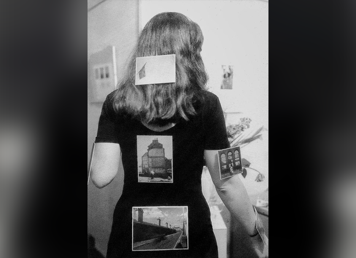 A woman pictured from behind with photos of architecture affixed to her clothing, hair, and body