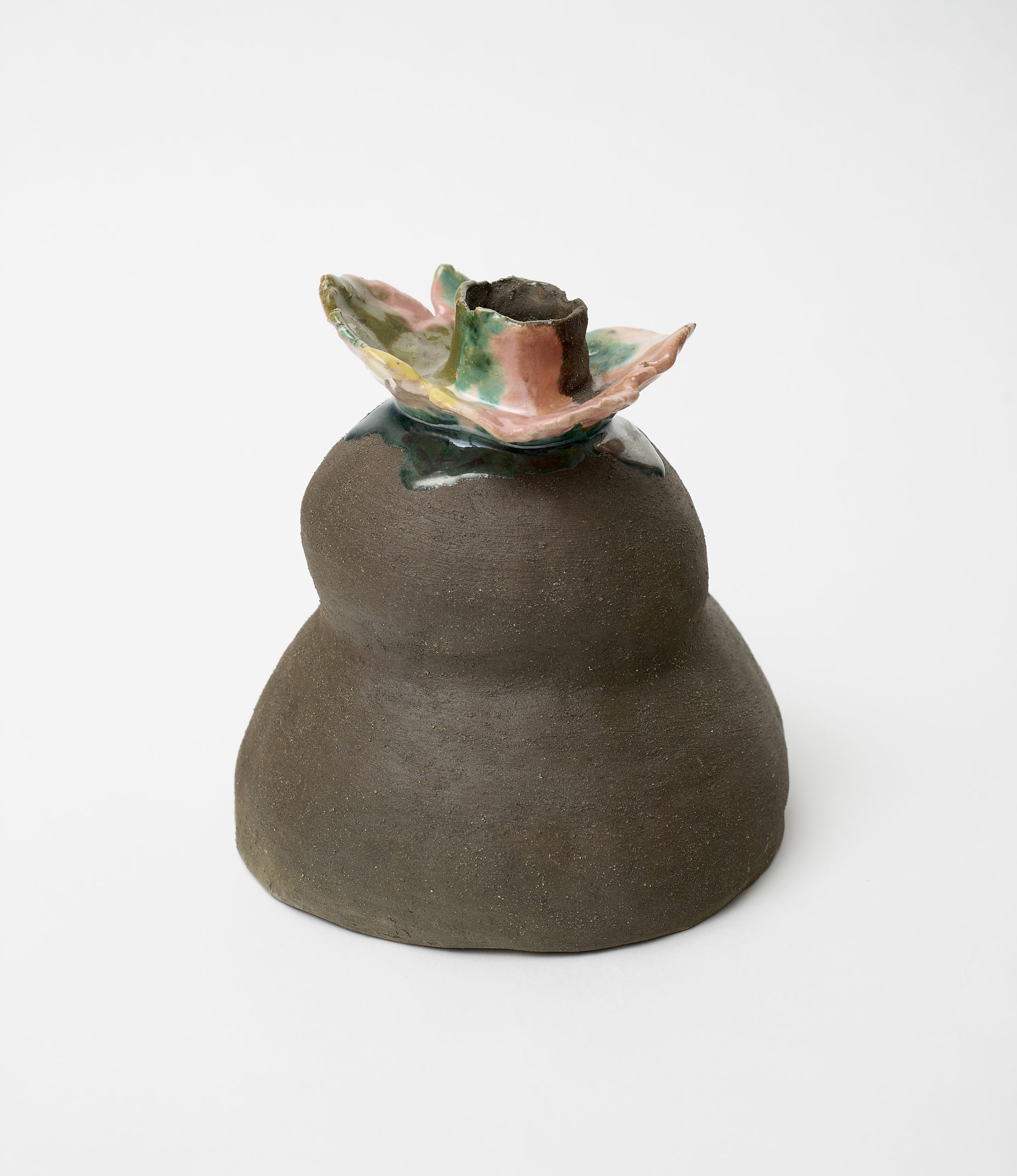 Image description: Earth-tone clay figure with rounded form and glazed floral-shaped top with pastel pink and dark green colors