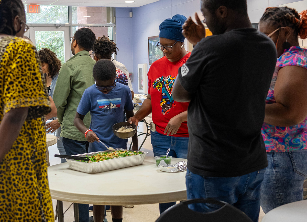 A group of people at a table with a large serving platter of vegetables