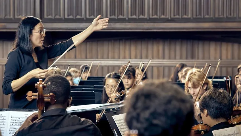 Image showing conductor with hand raised, conducting orchestra.