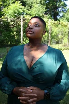 A woman with short black hair and teal blue blouse staring into the distance