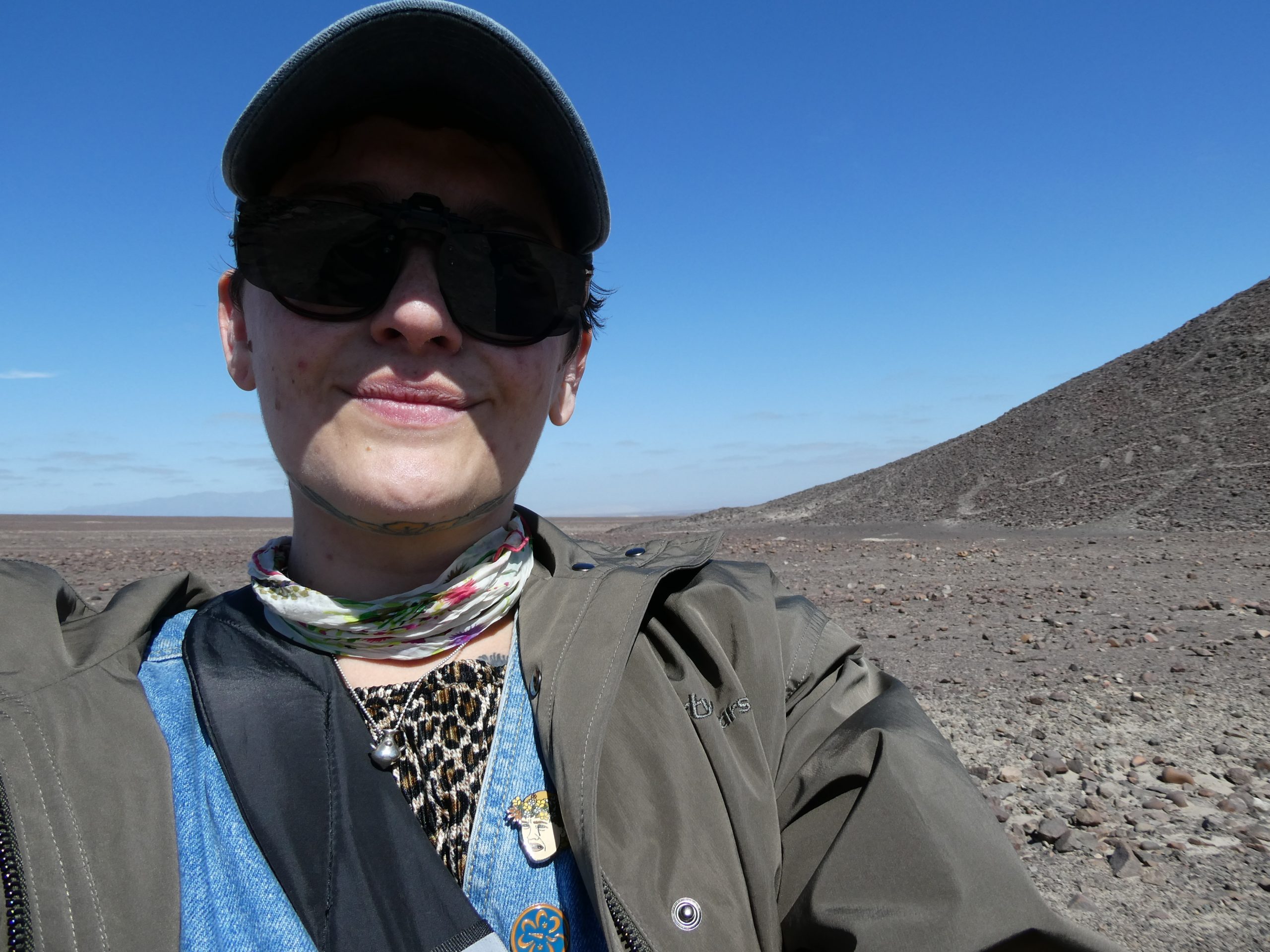 Image of Cassidy. Cassidy has on a cap and sunglasses and is wearing a green jacket