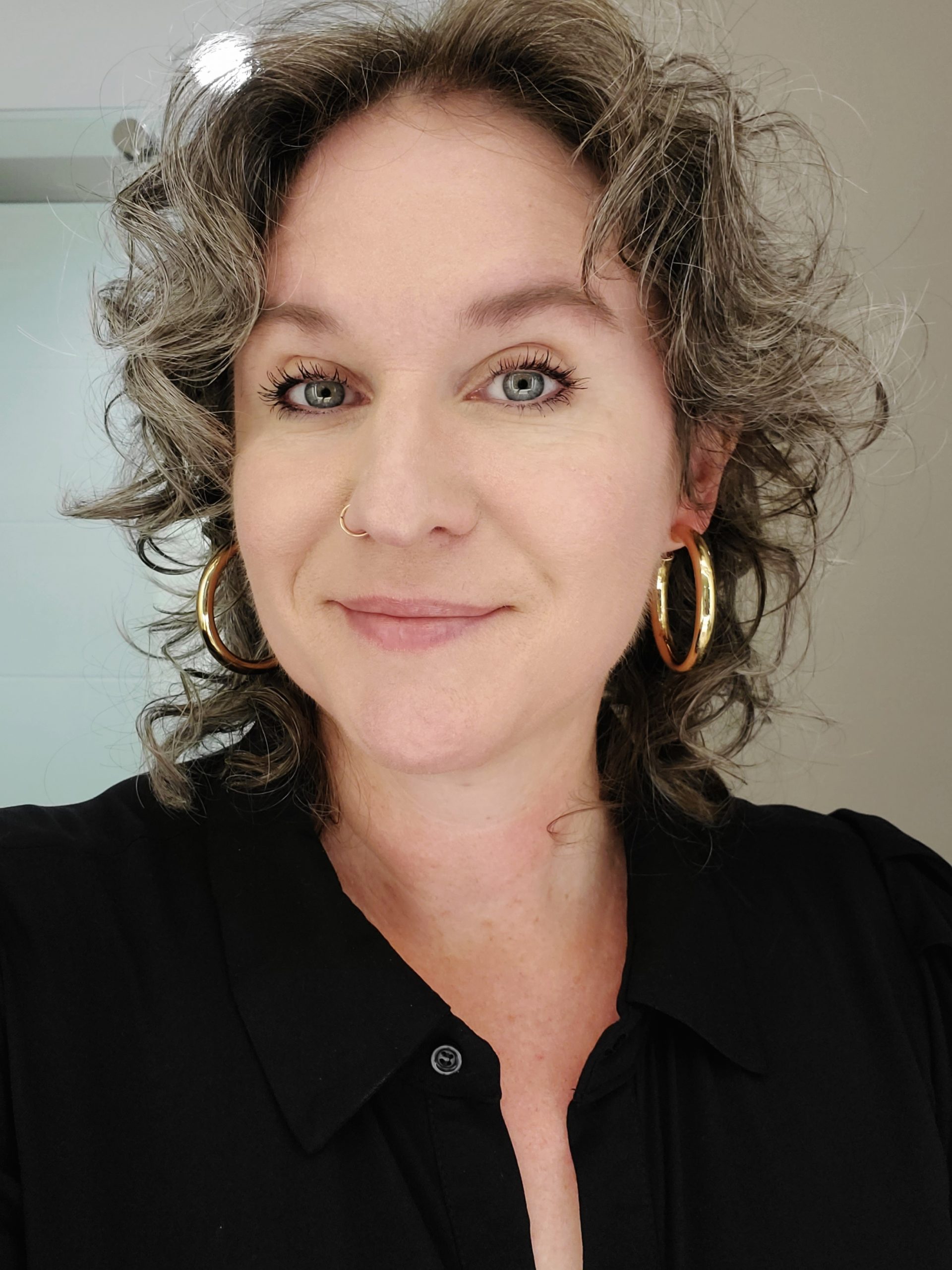 Selfie of Christy. Christy has shoulder length curly blonde hair and a black blouse.