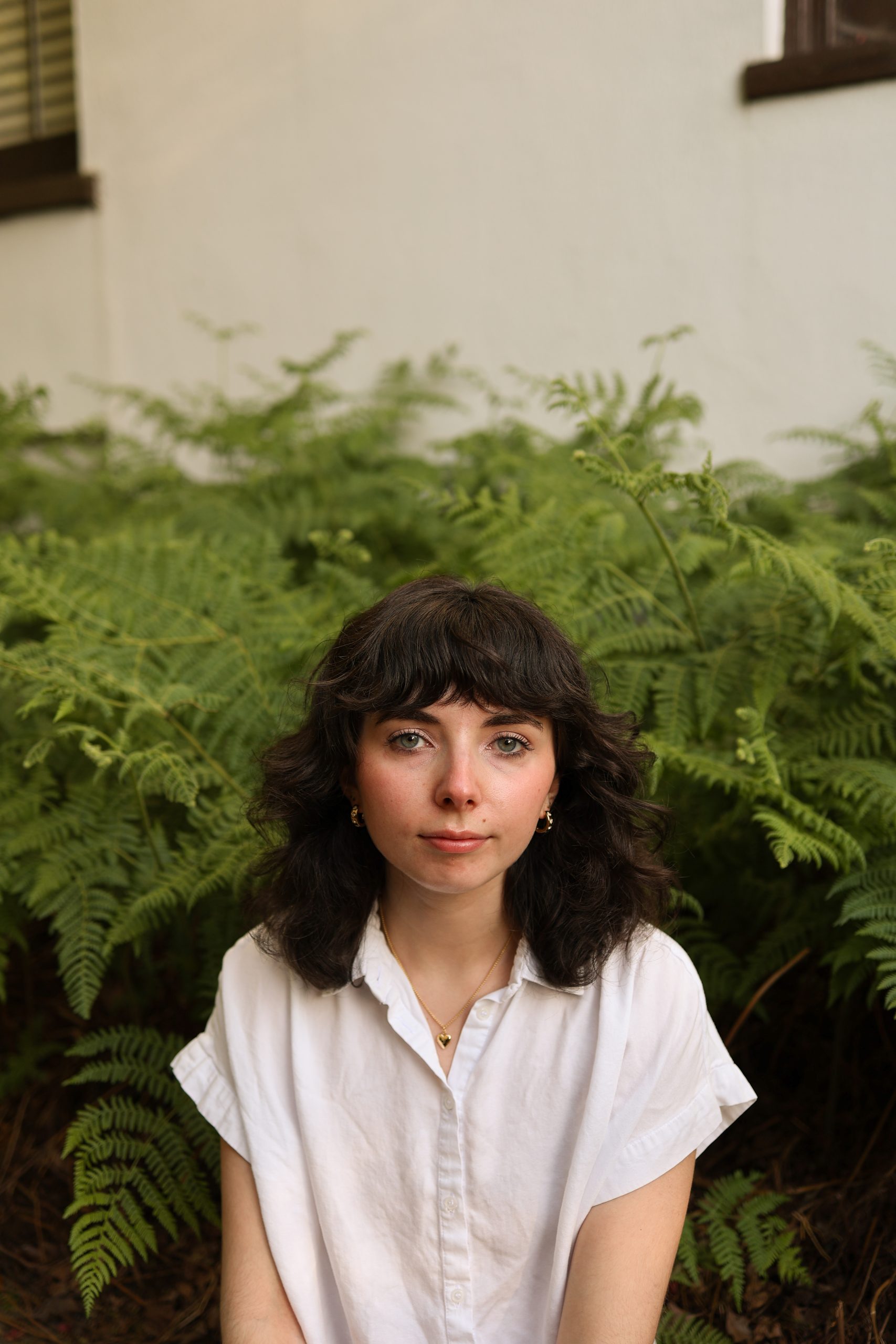 Image of Gabriela. Gabriel has shoulder length curly brown hair with bangs and is wearing a white blouse.