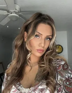 Selfie of Siraye. Siraye has medium length brown hair and is wearing a red and black patterned shirt.