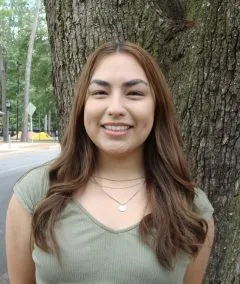 Image of Azariah. Azariah has medium length red hair and is wearing a green shirt.