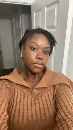 Image of Genesis. Genesis has short black hair and is wearing an orange sweater.