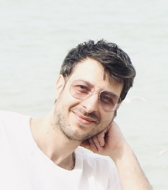 Image of Hesam wearing a white shirt with pink sunglasses. Hesam has short brown hair