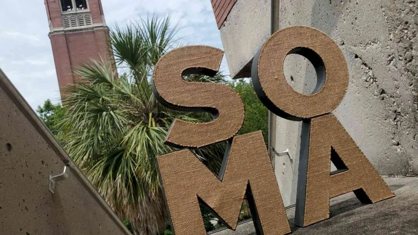 SOMA letters with Century Tower with palm trees in the background.