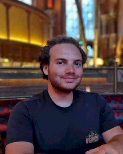 Photo of Brandon Markson. Brandon has short curly brown hair and a blue t-shirt on.