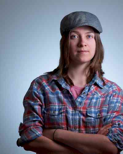 Photo of Jane K. Jane is wearing a grey cap and a red and blue flannel. Jane has medium length brown hair