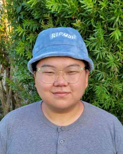 Photo of Xiaowei Cao. Xiaowei has a blue bucket hat, clear glasses, and a grey shirt.