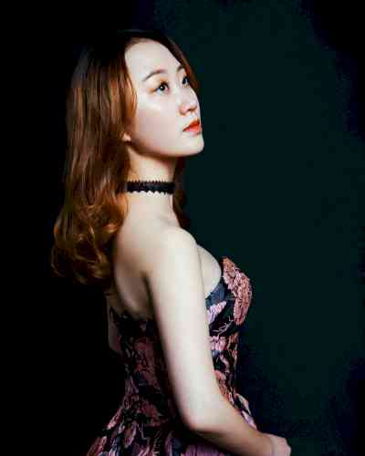 Photo of Yimian Mi. Yimian has long red hair and is wearing a black dress with a floral pattern
