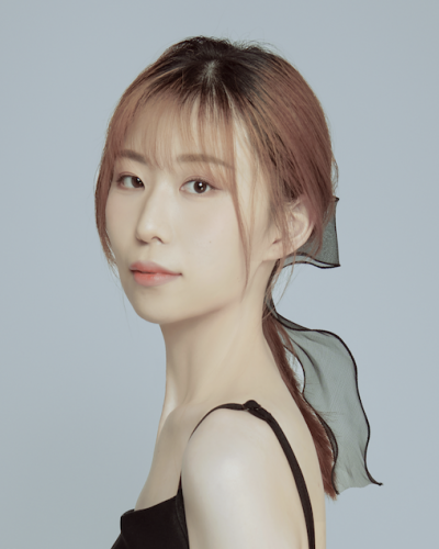 Photo of Yunmeng Su. Yunmeng has pink hair with bangs in a pony tail with a black bow. She is wearing a black top.