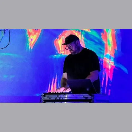 Photo of Kevin DJ-ing. Kevin has glasses, a black hat, and a black t-shirt.