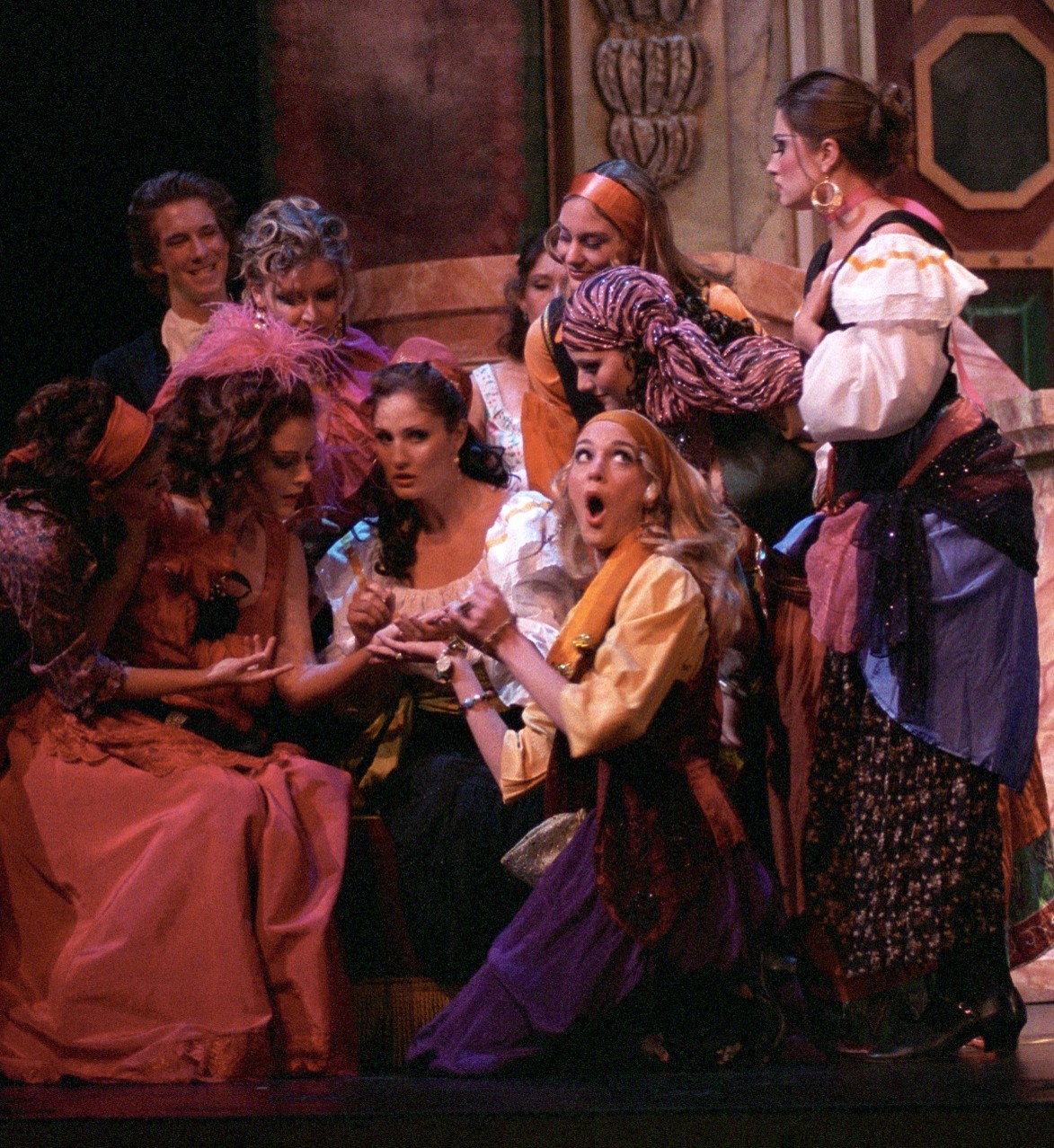 Photo of stage during an opera mid-performance. Shows many characters huddled around seemingly in discussion.