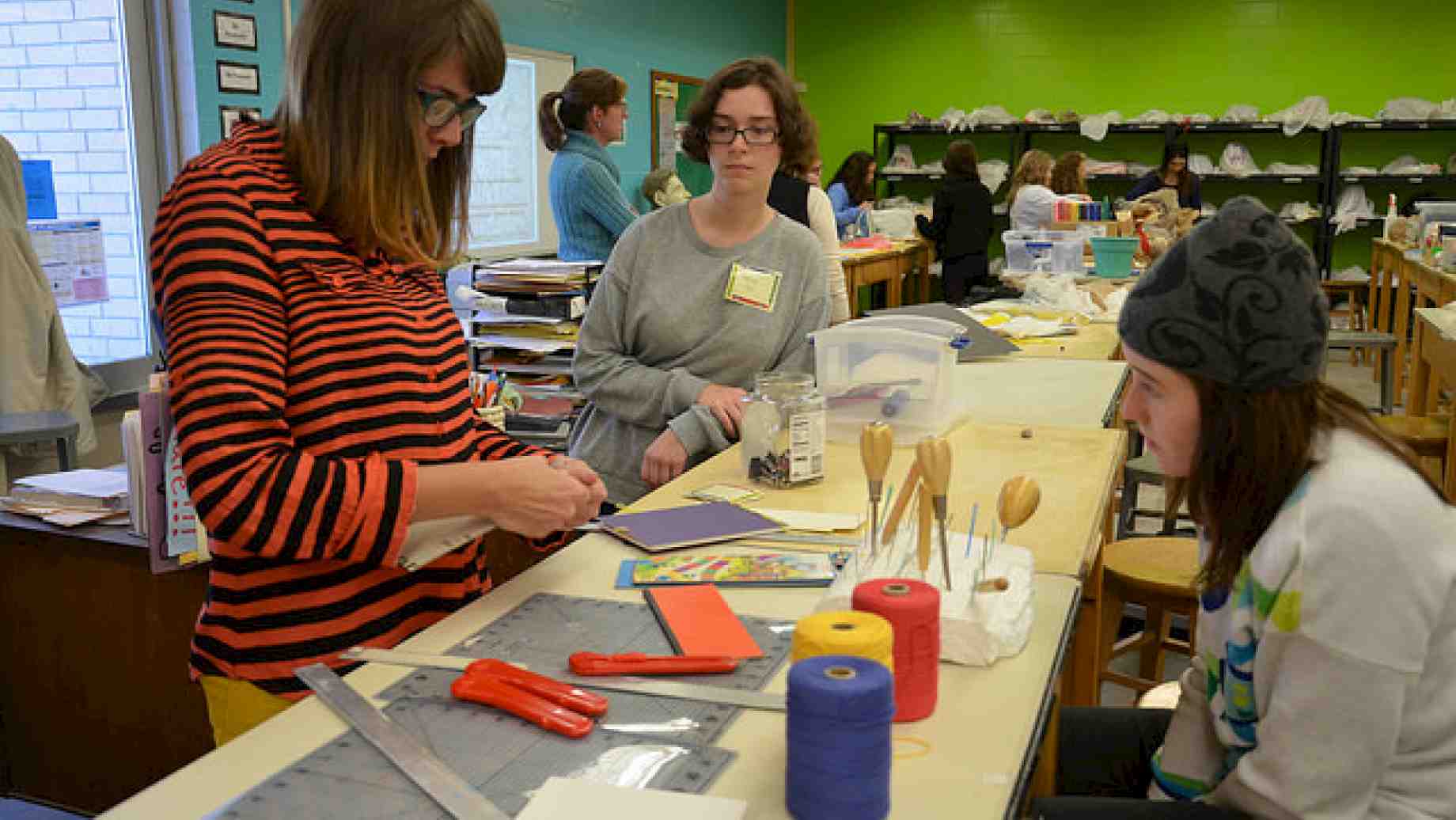 Graduate art education studnt demonstrating bookbinding techniques during a local field experience.